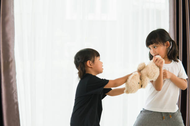 istock two little girl fighting over bear 1327905865