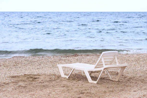 istock a lonely chaise longue on a sandy beach by the sea 1327906977