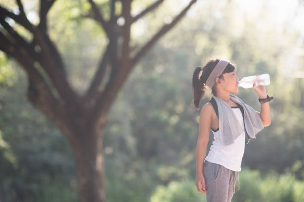istock Cute asian girl drinks water from a bottle outdoors  with sunllight 1327907090