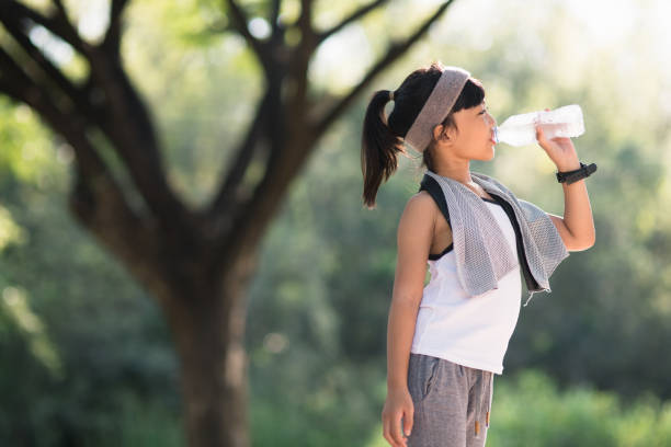 istock Cute asian girl drinks water from a bottle outdoors  with sunllight 1327907138