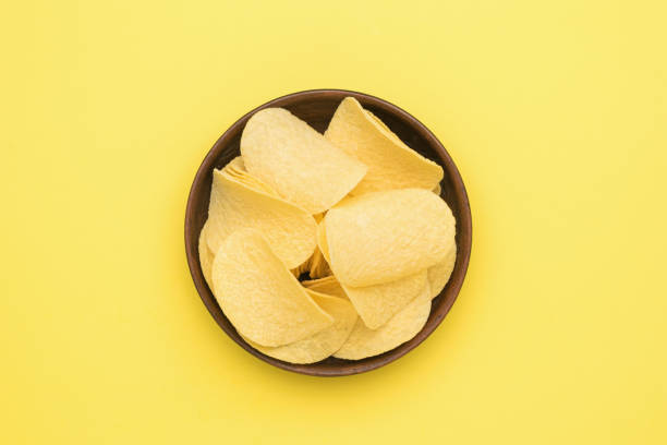 istock A clay bowl with potato chips on a yellow background. Flat lay. 1327913020