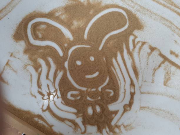 istock A girl draws a bunny on a light table. Drawing sand 1327915792