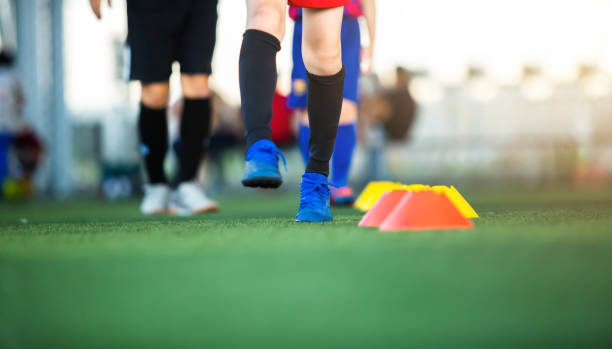 istock Selective focus to cone marker with blurry soccer team is on green artificial turf. 1327918738