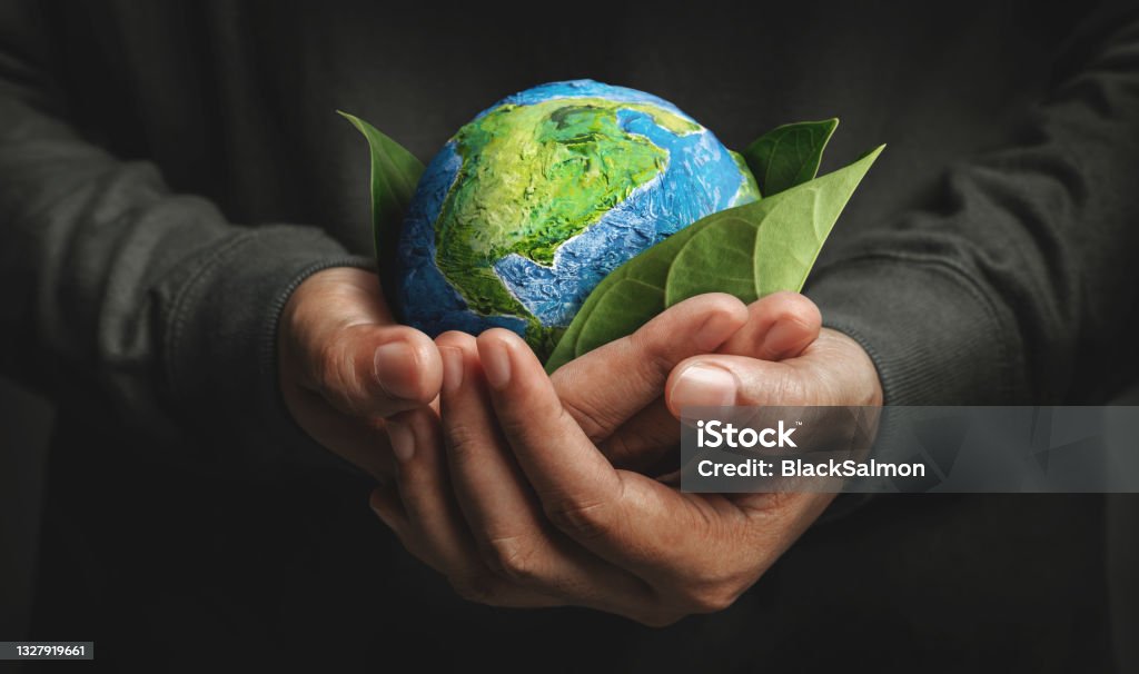 World Earth Day Concept. Green Energy, Renewable and Sustainable Resources. Environmental and Ecology Care World Earth Day Concept. Green Energy, Renewable and Sustainable Resources. Environmental and Ecology Care. Hand Embracing Green Leaf and Handmade Globe Environment Stock Photo