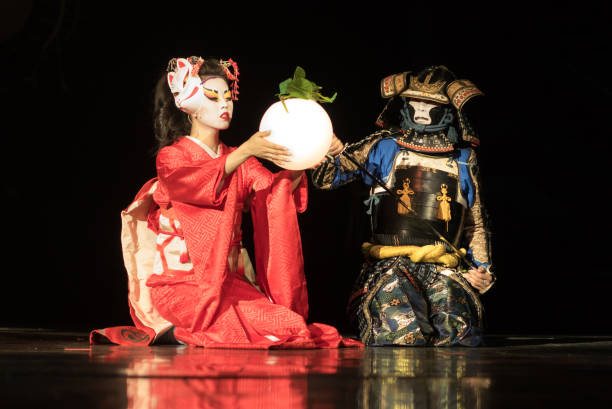 gueixas japonesas em quimono tradicional e máscara de raposa segurando lâmpada de esfera e guerreiro samurai em armadura estão sentados de joelhos no escuro. performance tradicional japonesa. - kabuki - fotografias e filmes do acervo