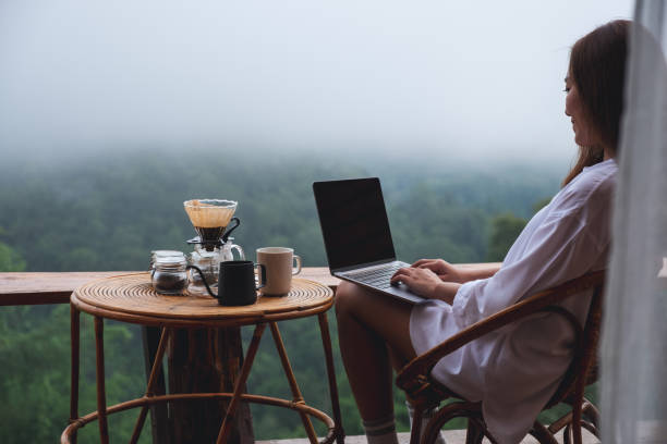 istock A woman using and working on laptop computer while sitting on balcony with a beautiful nature view on foggy day 1327924024