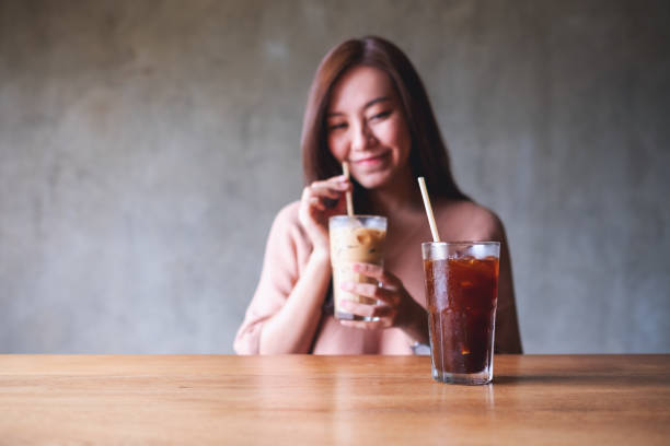istock A beautiful young woman holding and drinking iced coffee while looking at another drinks on the table 1327924056