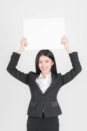 Portrait young working woman in black suit smiling and holding a blank space for advertising banner , space on white background, copy space