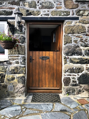 A half open wooden stable door in a picturesque Cornwall countryside stone cottage￼