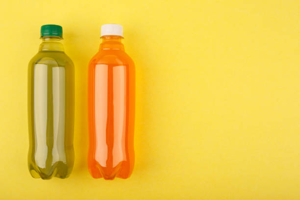 istock Orange and green refreshing soda drinks in plastic bottles on yellow background 1327935516