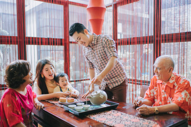 istock Chinese father serving chinese tea during multi generation enjoying traditional mid-autumn mooncake and chinese tea at home during afternoon tea gathering 1327937727