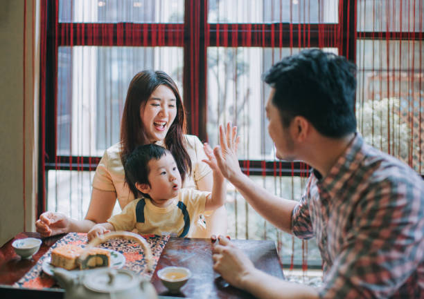 chinese father high five with son during enjoying traditional mid-autumn mooncake and chinese tea at home during afternoon tea gathering - midautumn festival 個照片及圖片檔