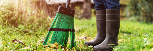 istock Janitor in rubber boots sweeping dry yellow leaves from autumn footpath 1327938098