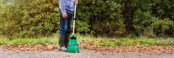 istock Worker with broom in hands stands on sidewalk covered with dry foliage 1327938105
