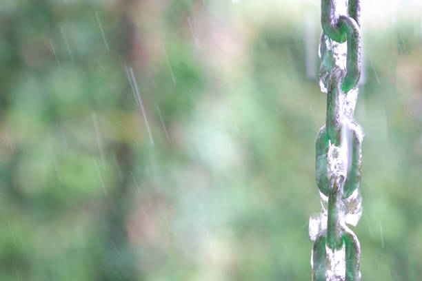 Water dripping and flowing down chain links with raindrops and nature background. Copy space.
