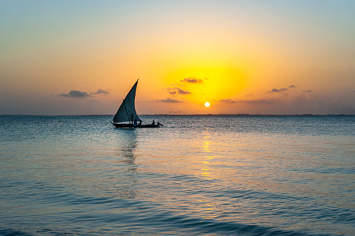 An Afrikan fishing sailboat Ngalawa  on beaitiful sunset background near Mnemba island, Tanzania