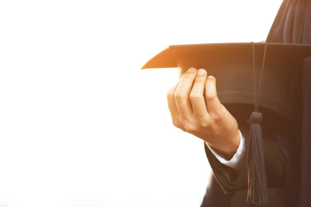 close up people show hand hold show hat in background School building. Shot of graduation cap during Commencement University Degree Concept , Celebration Education Student Success Learning Concept. stock photo