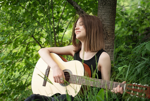Teenager girl playing guitar in the park