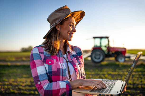 agricultor con ordenador portátil delante del tractor - farmer rural scene laptop computer fotografías e imágenes de stock