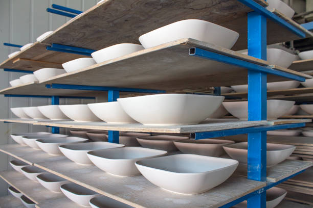 istock Blanks of white ceramic unfired dishes standing in rows on metal racks 1327946975