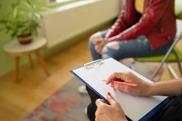 Close up of a female psychologist taking notes and a students knees Close up of a psychologist notes and a students knees during a mental health meeting in a stylish office mental health professional stock pictures, royalty-free photos & images