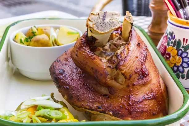 Photo of Traditional Czech roasted pork knuckle meat served with potatoes and vegetables