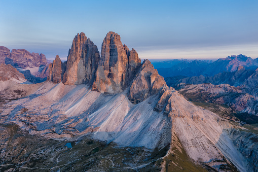 Aerial view of Tre Cime peaks at pink sunset light, Dolomites Alps. National Nature Park, Italy.