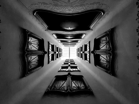 Black and white abstract background image. Perspective view of the interior of a building. Useful image for concepts of success, reaching a goal, reaching the top. It shows between light and shadow the path to follow to achieve a goal.