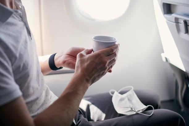 istock Passenger with face mask drinking coffee in airplane 1327963126