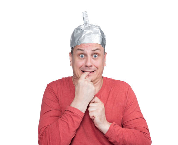 Emotionally scared man wearing aluminum foil hat holds finger in mouth, isolated on white background. File contains a path to isolation. Fear and phobia concept Emotionally scared man wearing aluminum foil hat holds finger in mouth, isolated on white background. File contains a path to isolation. Fear and phobia concept tin foil hat stock pictures, royalty-free photos & images