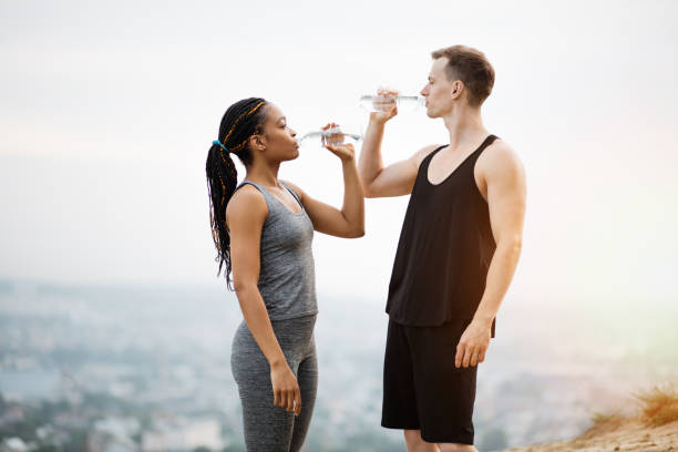 istock Multiracial couple drinking water after outdoors activity 1327969496