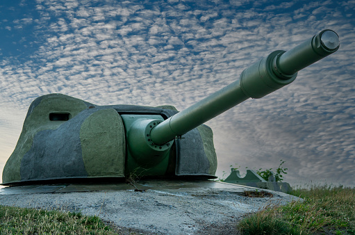 High caliber cannon in a defensive position on a hillside. Cold war conflict weapons overlooking the sea.