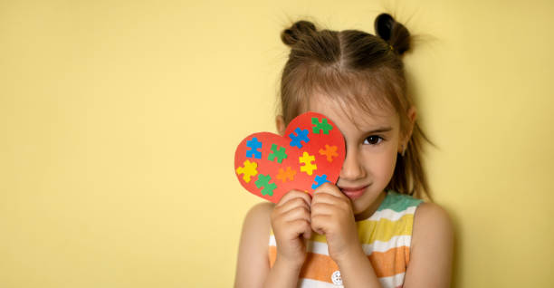 World Autism Awareness Day. Banner A beautiful girl holds a heart with colorful puzzles in her hands, covering one eye. World Autism Awareness Day. Banner autism photos stock pictures, royalty-free photos & images