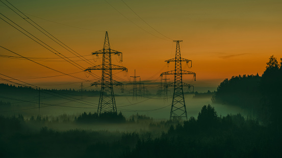 High voltage power poles in the evening fog in summer sunset