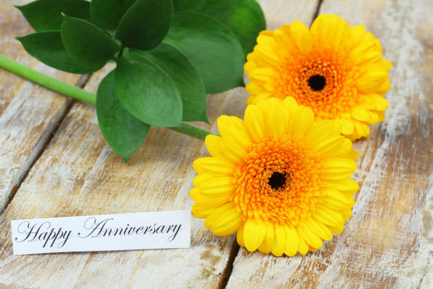 istock Happy Anniversary card with two yellow gerbera daisies on rustic wooden surface 1327974310