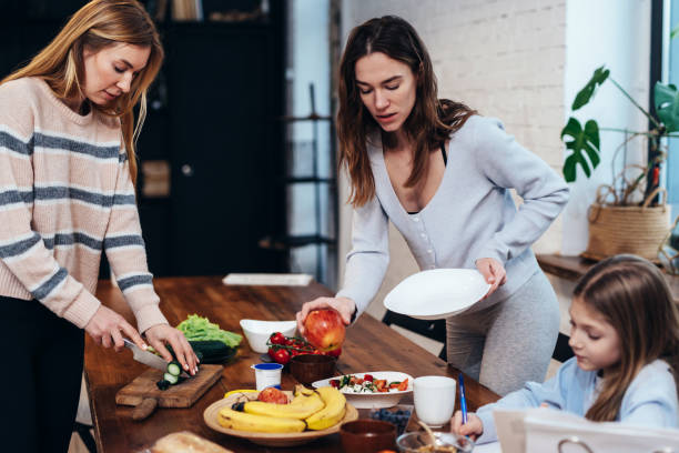 istock Young women set the table, girl does her homework 1327975044