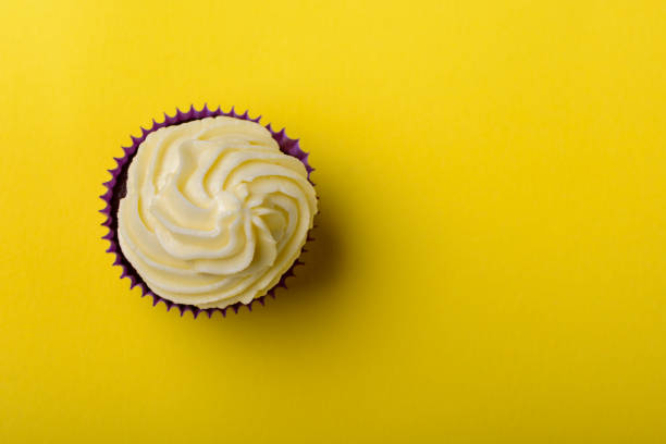 istock Cupcake in purple wrap on yellow background. Minimalism. Top view with copy space. 1327978534