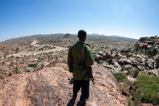 Laas Geel, Somaliland - Jan 24, 2014: Back view of a Somaliland police force overlooking the wilderness from the top of the hill