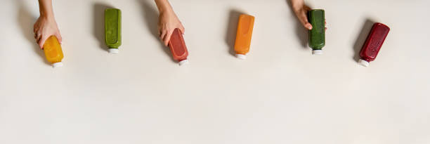 Flat-lay of human hands holding fresh juices in bottles