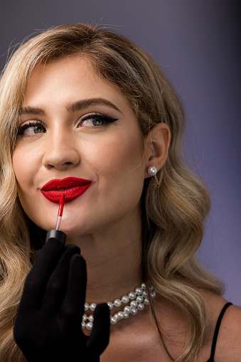 Sophisticated woman applying bright red lipstick
