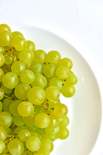 istock Green juicy delicious grapes on a white plate 1327982941
