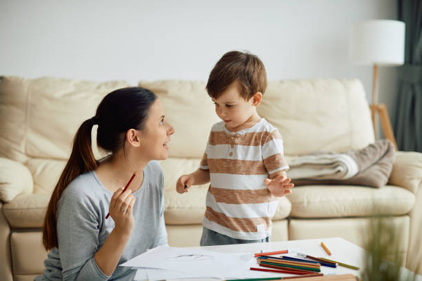 自宅で紙に絵を描きながら息子と話す若い母親。 - 2歳から3歳 ストックフォトと画像