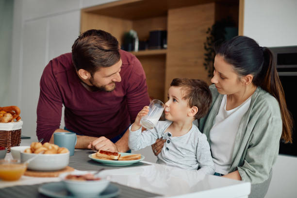 Young happy family enjoying while having breakfast together at home.