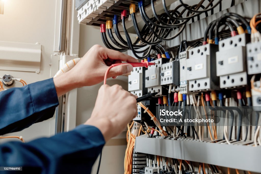 Electrician engineer uses a multimeter to test the electrical installation and power line current. Electrician engineer uses a multimeter to test the electrical installation and power line current in an electrical system control cabinet. Electric Switchboard Stock Photo