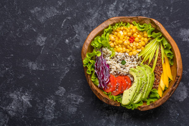 istock Buddha bowl with chickpea, avocado, wild rice, quinoa seeds, bell pepper, tomatoes, greens, cabbage, lettuce on dark stone table. Vegetarian super food. Top view with copy space. 1327988334
