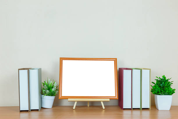 istock Mock up brown picture frame template for place image or text inside with a little tree on wood table. 1327988477