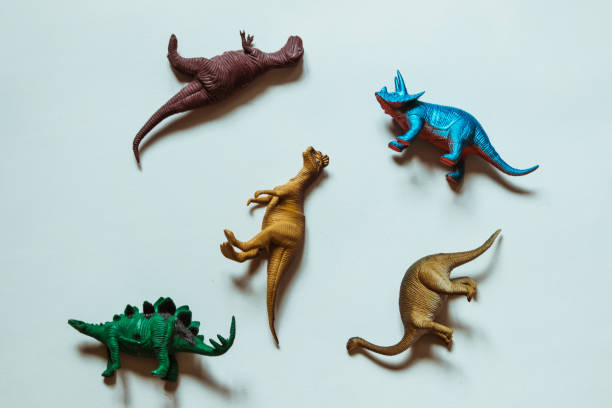 istock Five toy dinosaurs of different colors lie on a white background. 1327991846