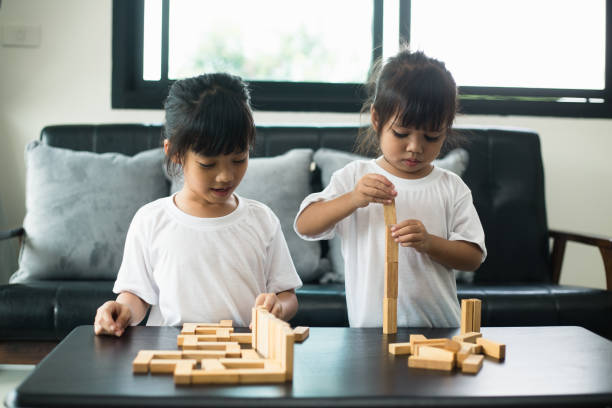 istock Two happy siblings playing a game with wooden blocks at home joyfully 1327994295