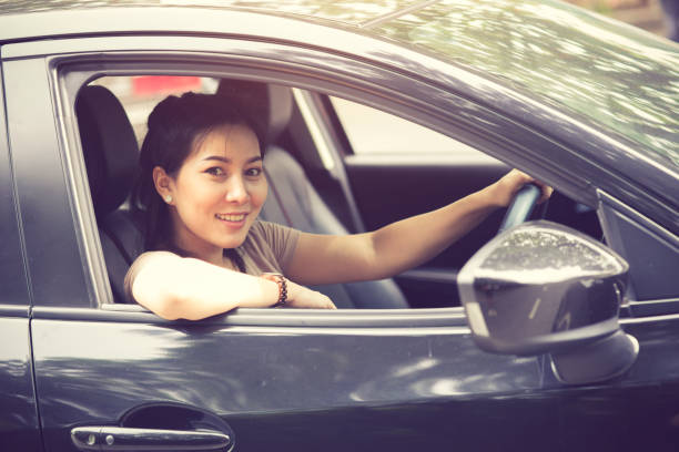 istock Beautiful girl  is smiling while driving a car 1327998889