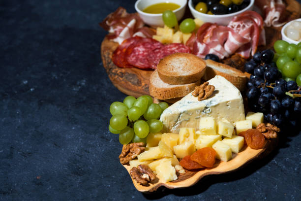 istock cheese platter on a wooden board, bread, fruit and cold cuts on dark background 1328000052